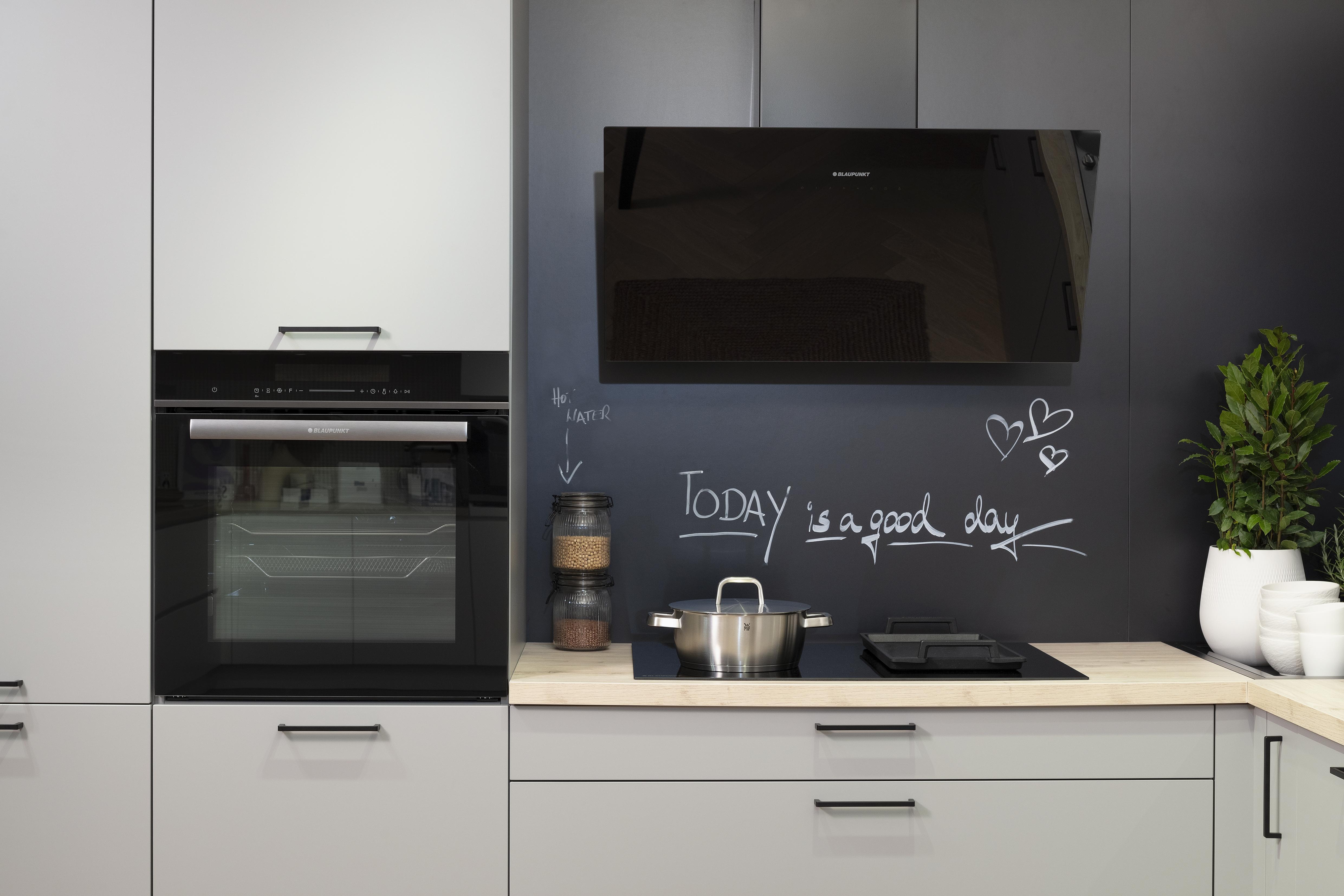 Häcker-Küche in Perlgrau Lacklaminat mit Kopffreihaube, Kochfeld und Backofen. 