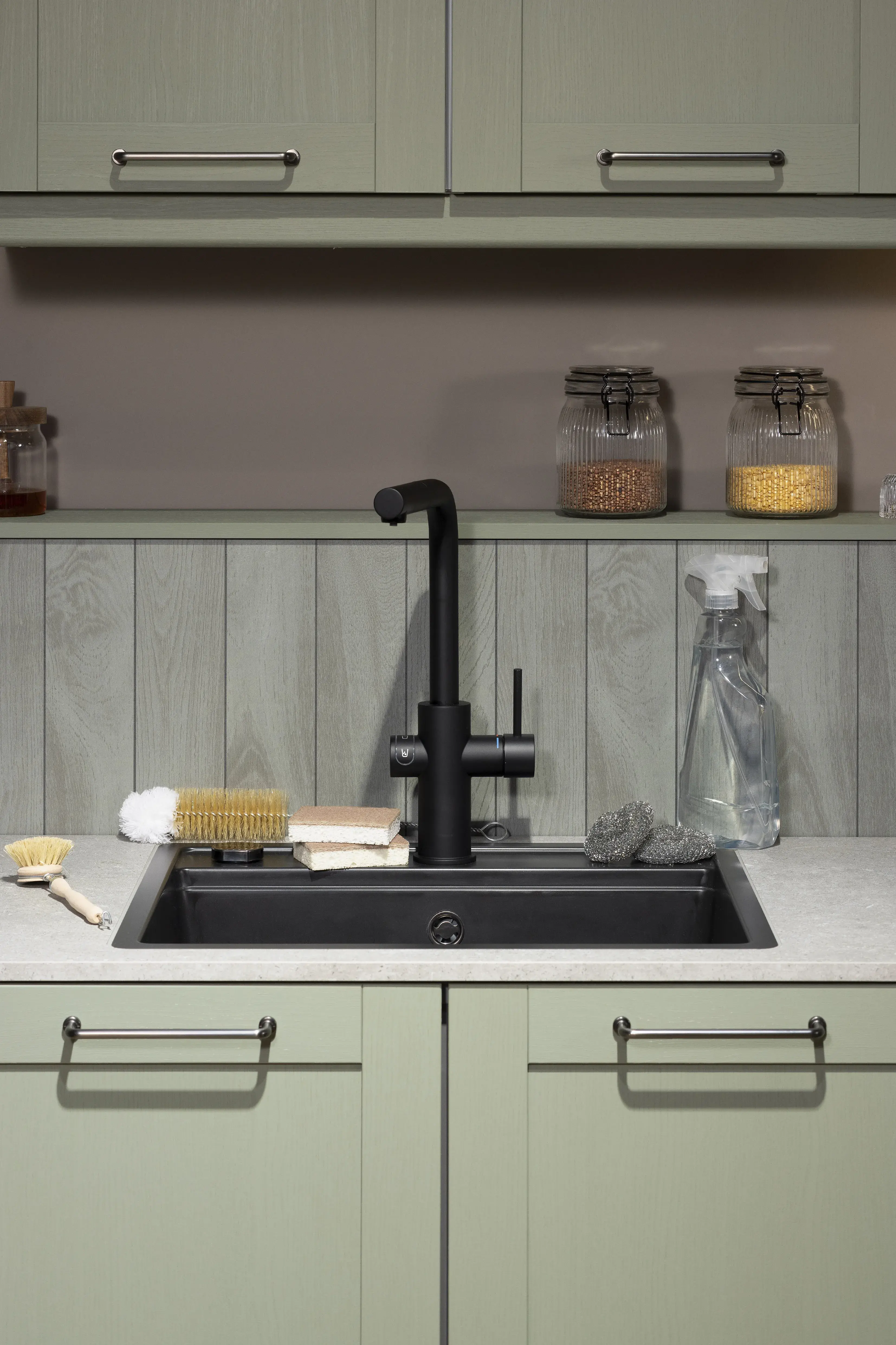 Moderne Spüle mit schwarzem Wasserhahn, Utensilien und Vorratsgläsern auf der Ablage.