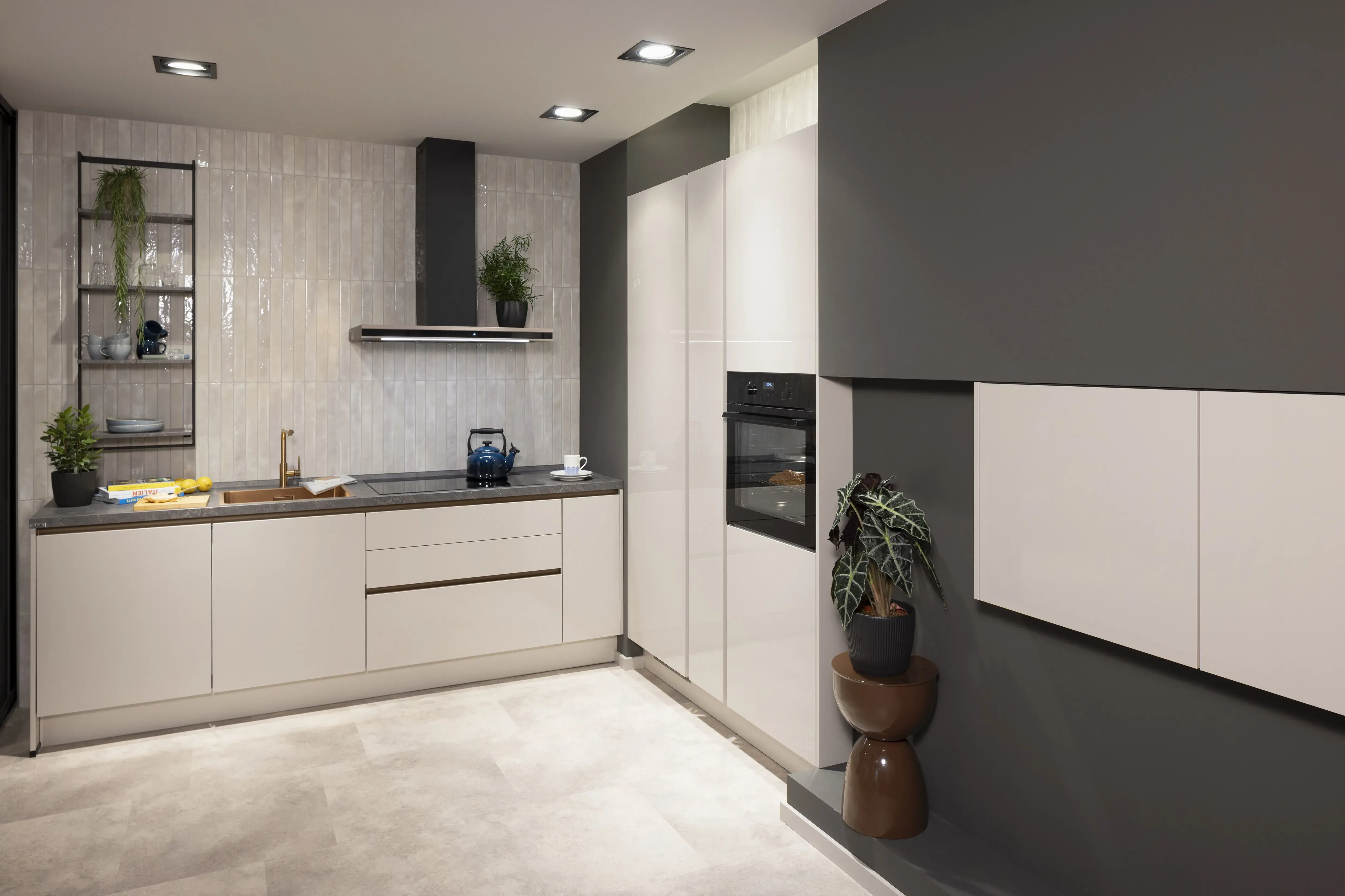Moderne Küche mit weißen Schränken, grauer Wand und eingebautem Backofen.
